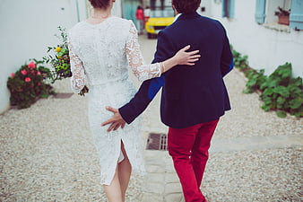 Couple walking away in white lace dress and red trousers