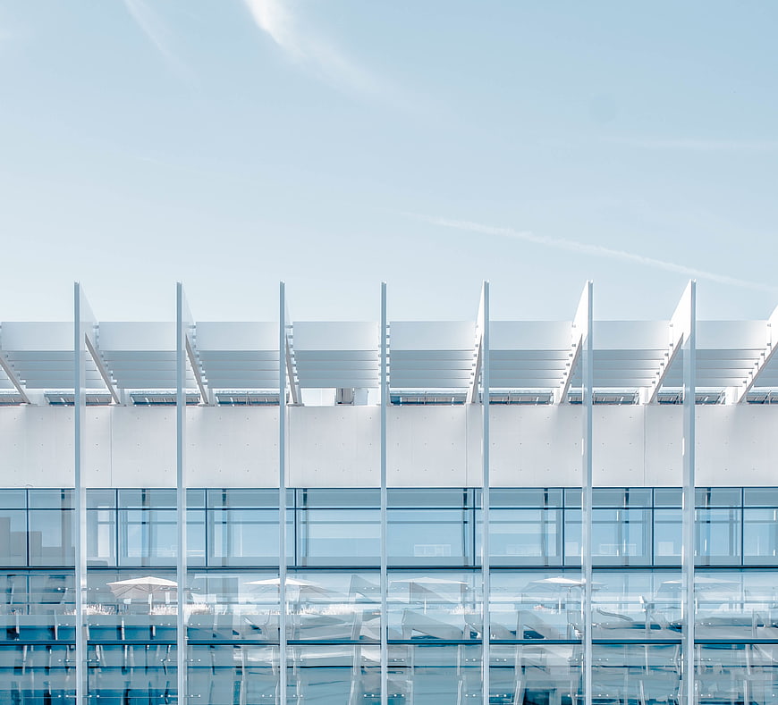 Modern white architectural facade with glass windows and blue sky