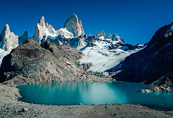 Turquoise glacial lake with jagged mountain peaks and hikers