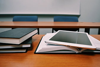 Tablet and Books on Wooden Desk in Classroom
