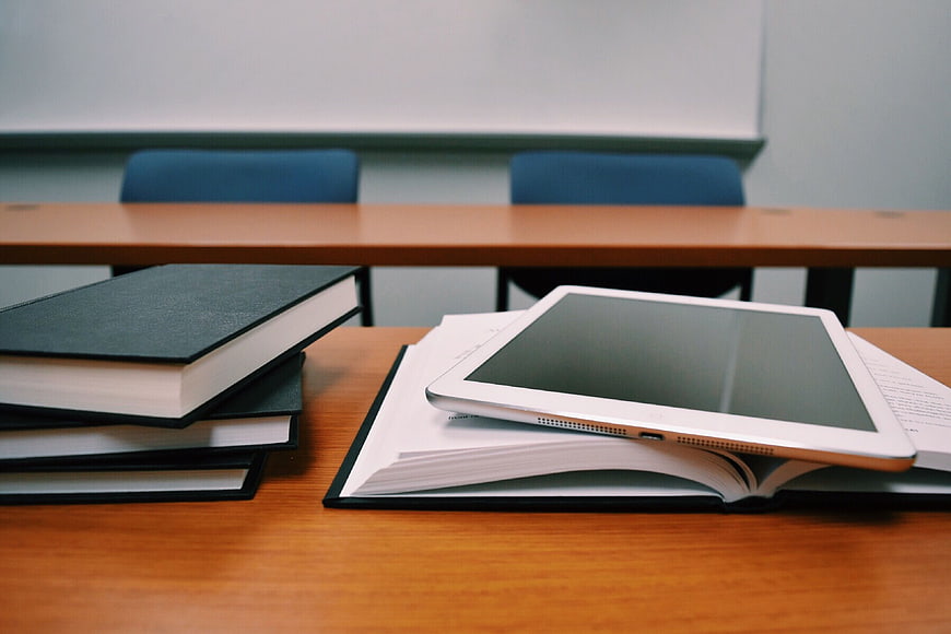 Tablet and Books on Wooden Desk in Classroom