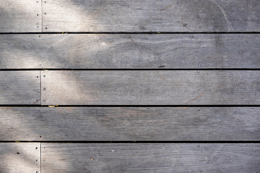 Weathered gray wooden deck planks with natural sunlight texture