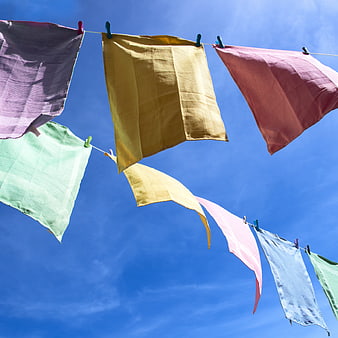 Colorful laundry hanging on a clothesline against a bright blue sky