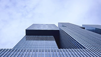 Low angle view of modern glass skyscrapers against cloudy sky