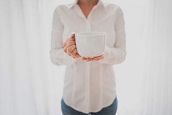 Woman in white shirt holding white coffee mug