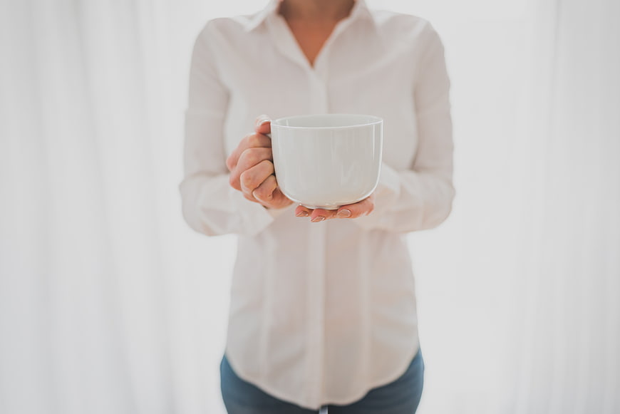 Woman in white shirt holding white coffee mug