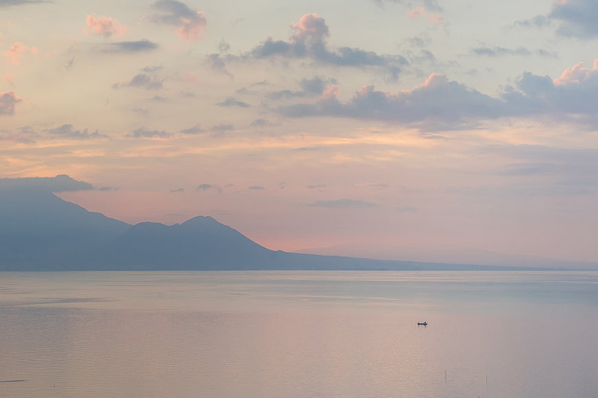 Serene Sunset Over Calm Sea with Distant Mountains
