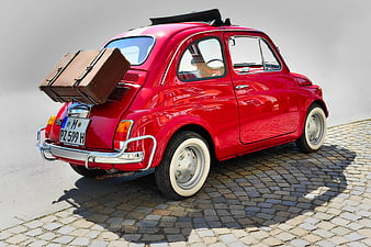 Rear View Of Red Vintage Fiat 500 With Vintage Suitcase On Cobblestone