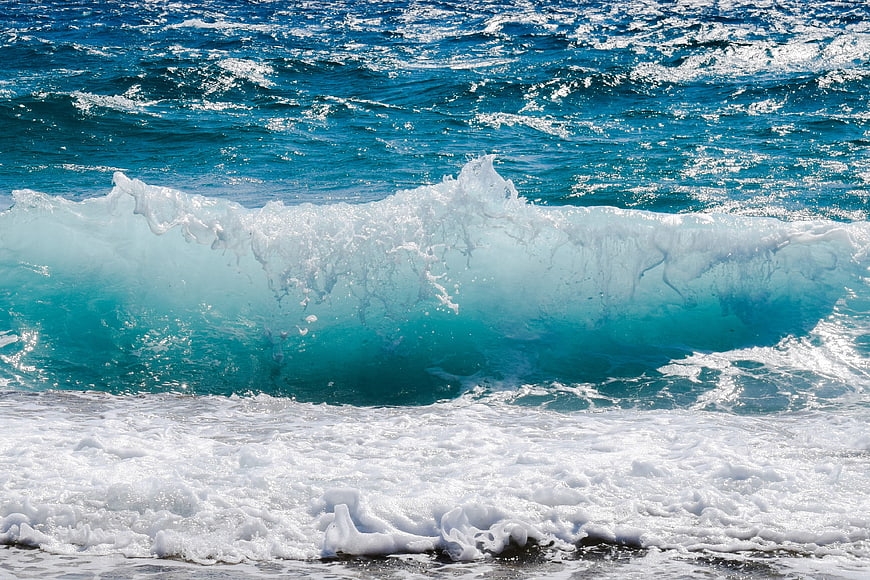 Dynamic turquoise ocean wave crashing with white foam