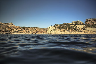 Low angle view of desert canyon lake with blue sky