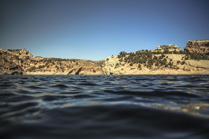 Low angle view of desert canyon lake with blue sky