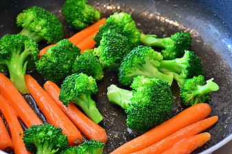 Fresh broccoli and carrots cooking in a frying pan