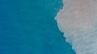 Aerial view of turquoise ocean waves crashing on white sand