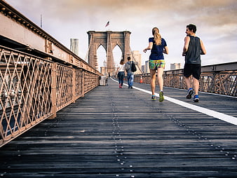 Couple jogging on Brooklyn Bridge wooden walkway