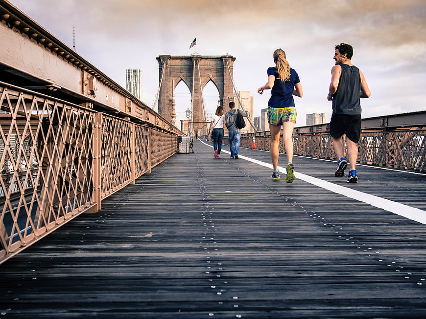 Couple jogging on Brooklyn Bridge wooden walkway