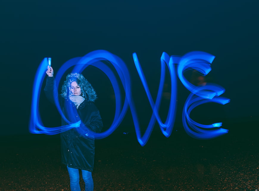 Woman writing LOVE with blue light painting at night