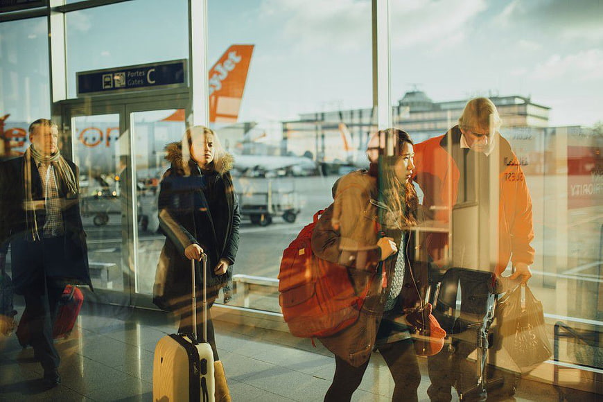 Travelers Walking Through Airport Terminal Window