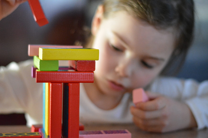 Child Playing with Colorful Wooden Building Blocks