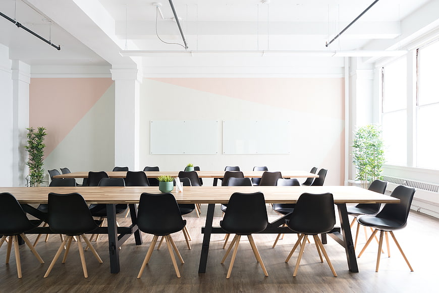 Modern bright office meeting room with wooden tables and black chairs