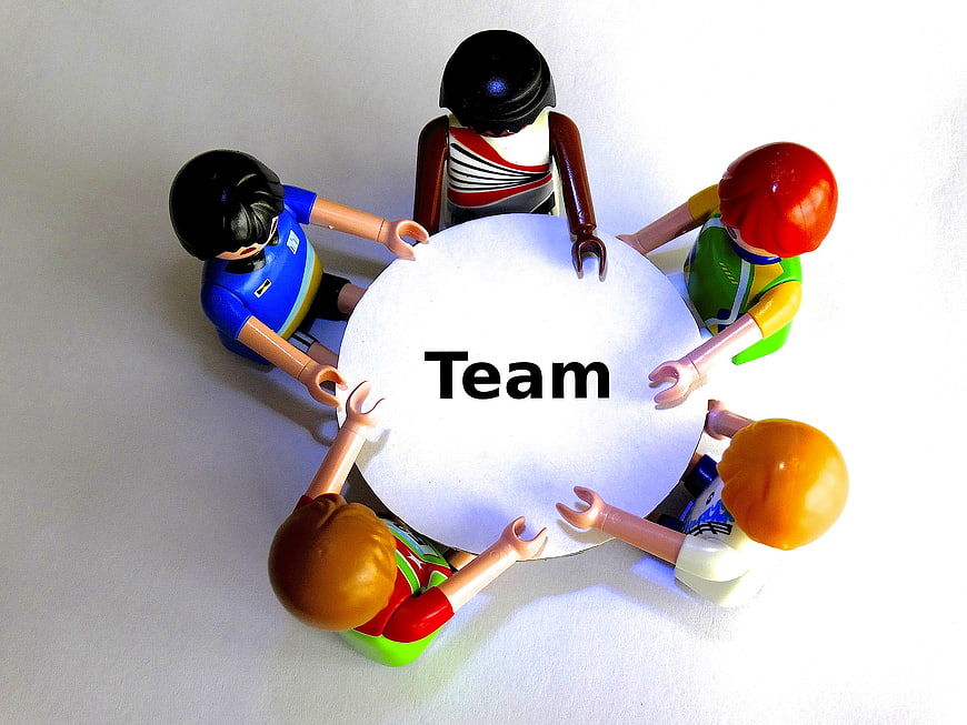 Playmobil figures around round table with Team text