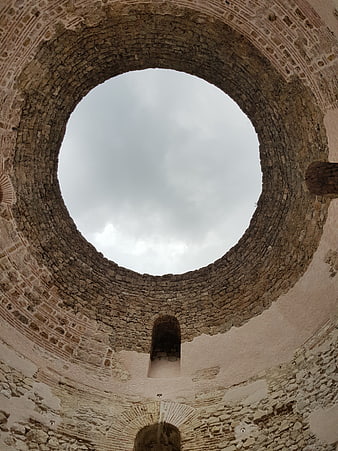 Low angle view of ancient stone tower interior looking up at sky