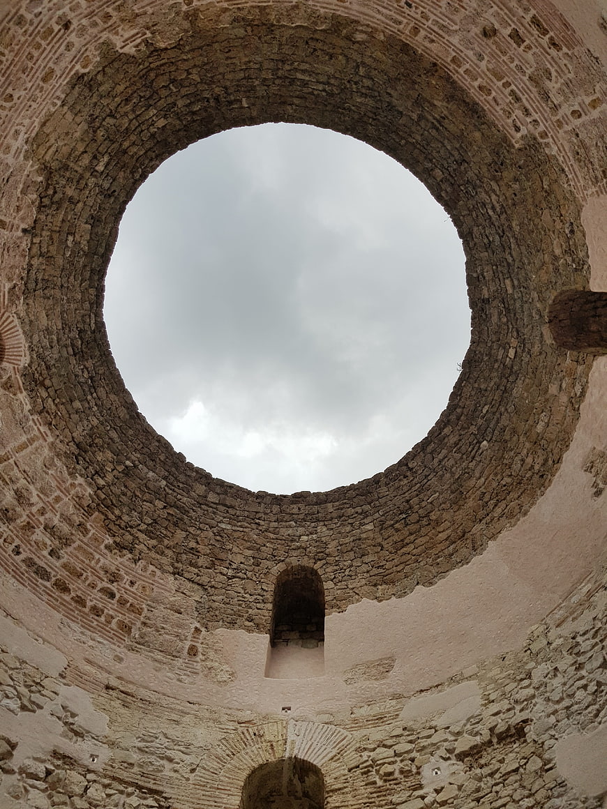 Low angle view of ancient stone tower interior looking up at sky