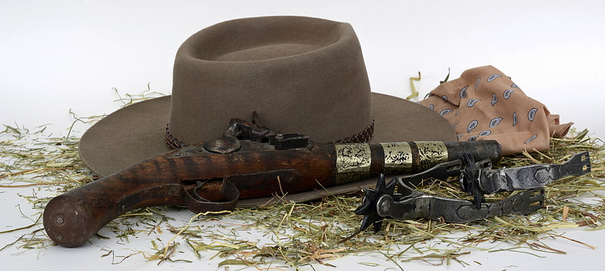 Antique Cowboy Pistol, Hat, Spurs, and Bandana on Hay