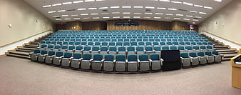 Empty University Auditorium With Rows Of Blue Seating And Wooden Stage