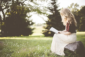 Young Blonde Woman Reading Book Outdoors in Nature