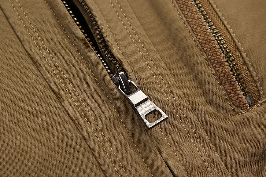 Close-up of a metal zipper pull on a tan jacket