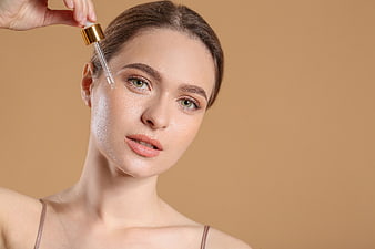 Woman applying serum dropper to face for skincare