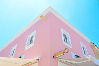 Low angle view of pink building corner with blue sky