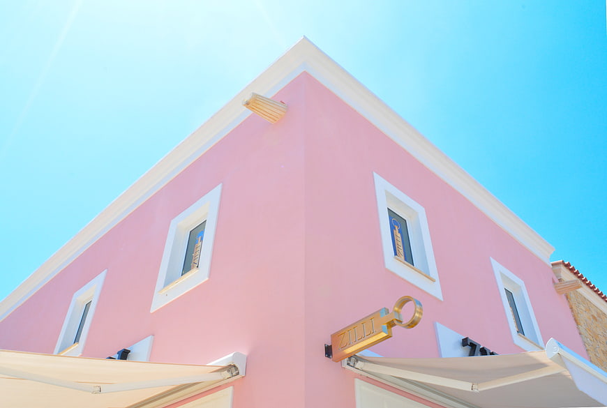 Low angle view of pink building corner with blue sky