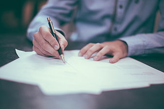 Close-up of hands signing a document with a pen