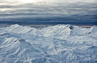 Snow-covered mountain range under dramatic cloudy sky