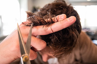 Close-up of hairdresser cutting brown hair with scissors