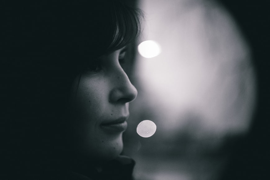 Moody Black and White Portrait of Woman Looking Out Window