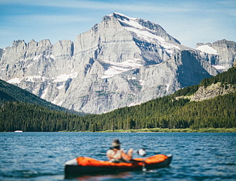 Kayaker on Mountain Lake with Snowy Peaks