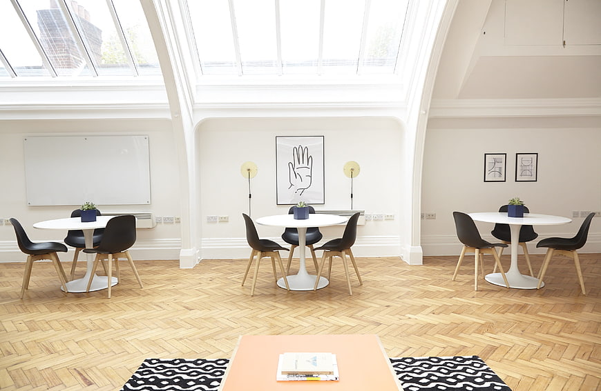 Bright Modern Office Lounge With White Tables And Black Chairs