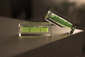 Two Green Spirit Levels Resting On A Wooden Workbench Surface