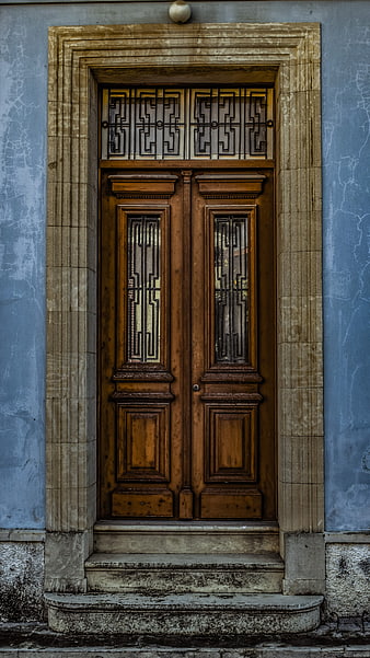 Vintage wooden double door with stone frame on blue wall