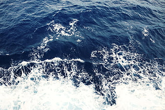 Aerial view of deep blue ocean waves with white foam