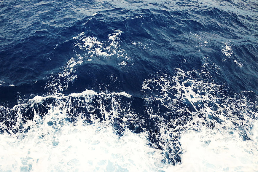Aerial view of deep blue ocean waves with white foam