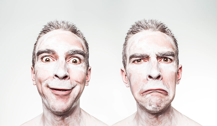 Man with white face paint showing happy and sad expressions