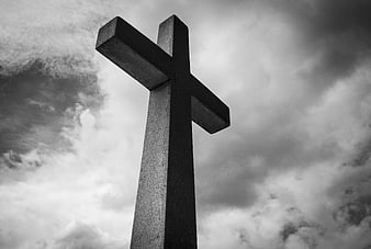 Black and white stone cross against dramatic cloudy sky