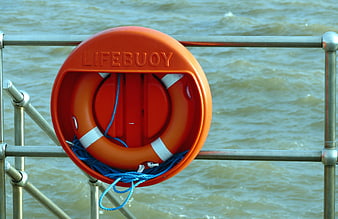Orange Lifebuoy on Metal Railing by Water