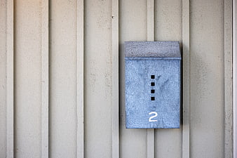 Blue metal mailbox with number two on beige siding