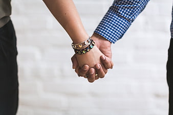 Close-up of couple holding hands with bracelets
