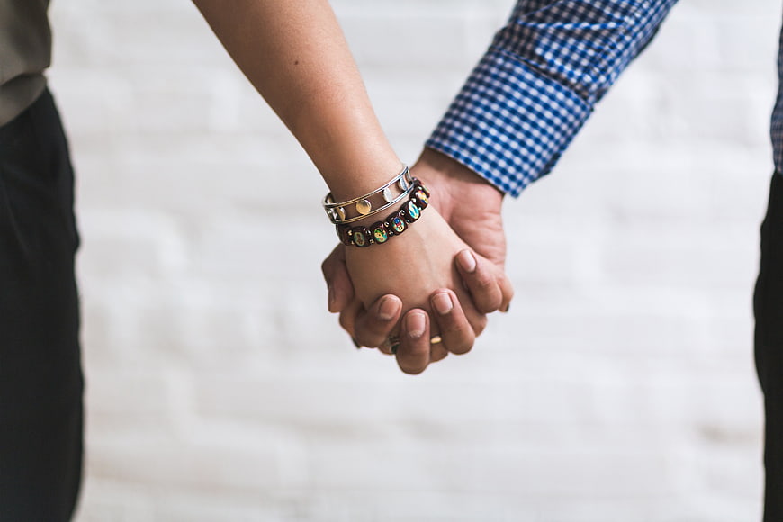 Close-up of couple holding hands with bracelets