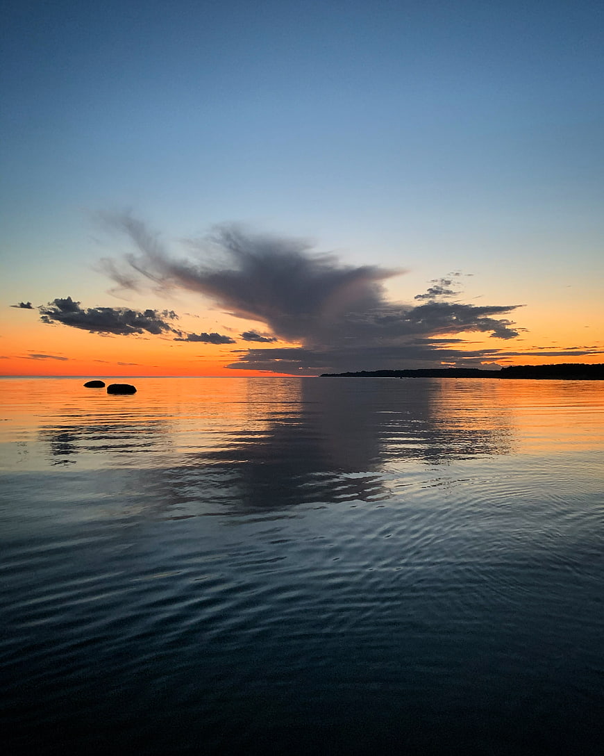 Serene Sunset Over Calm Ocean with Cloud Reflections